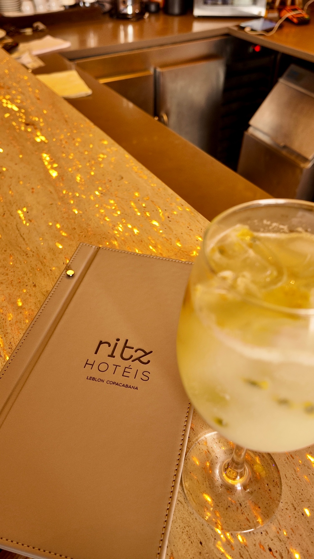 Cardápio Ritz Hotéis ao lado de drink no bar